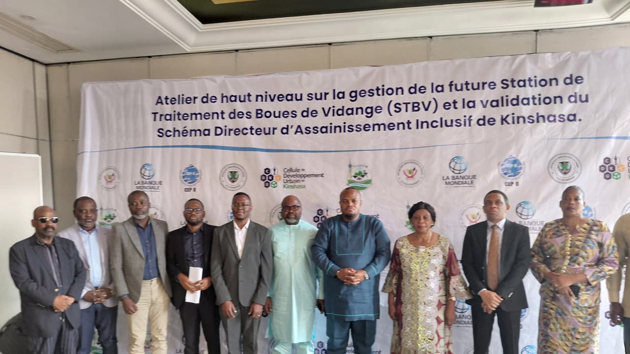 Participants et experts posant devant la banderole de l'atelier de haut niveau sur la future Station de traitement des boues de vidange (STBV) de Kinshasa, dans un hôtel de la capitale congolaise.