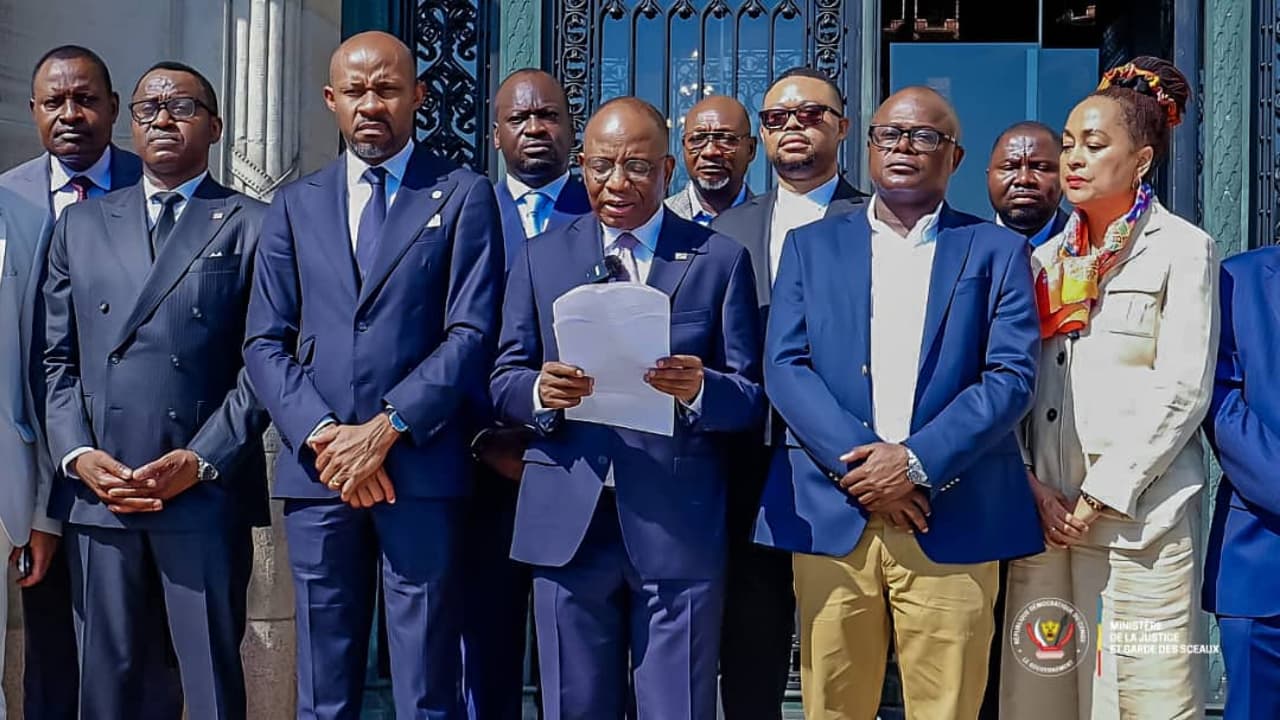 Le ministre d'État à la Justice Guillaume Ngefa lit une déclaration, entouré des membres de la délégation congolaise, devant les portes de bronze du Palais de la Paix à La Haye.