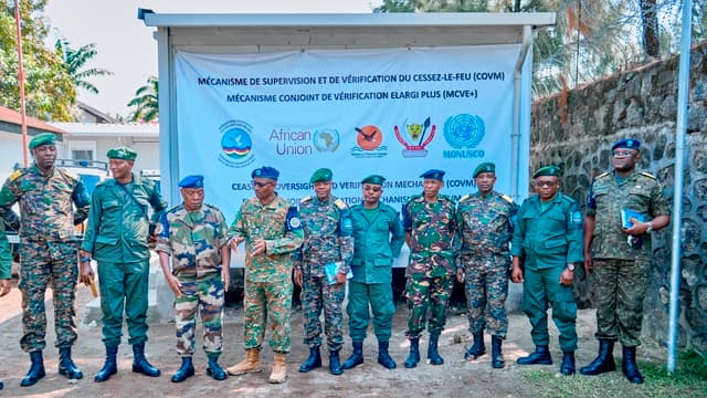 Une quinzaine d'officiers en tenues militaires différentes, dont plusieurs portant le béret bleu de l'ONU et des bérets verts, alignés devant une banderole blanche portant l'inscription « Mécanisme de supervision et de vérification du cessez-le-feu (COVM) ,  Mécanisme conjoint de vérification élargi plus (MCVE+) » et les logos de la CIRGL, de l'Union africaine, de l'Alliance Fleuve Congo, des FARDC et de la MONUSCO, dans une cour en terre battue à Goma.
