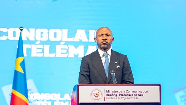Patrick Muyaya, ministre de la Communication et porte-parole du gouvernement congolais, debout derrière un pupitre portant la mention « Briefing - Processus de paix, Kinshasa, le 17 juillet 2026 », à côté du drapeau de la RDC