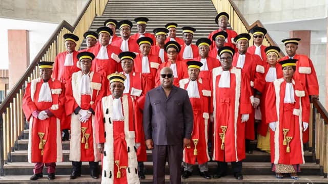 Hauts magistrats congolais en robe rouge d'apparat, coiffés de la toque, réunis sur les marches d'escalier aux côtés du président Félix Tshisekedi en costume sombre lors d'une audience solennelle de la Cour de cassation à Kinshasa.