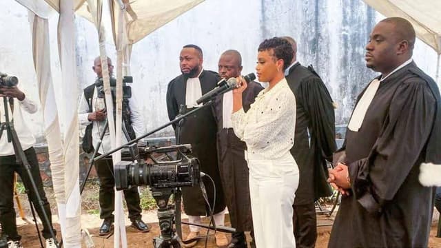 La chanteuse Rebo Tchulo, en chemisier blanc à pois, debout au micro et entourée de ses avocats en robe noire, lors d'une audience du tribunal militaire de garnison de Ngaliema, sous une tente et devant les caméras de la presse.