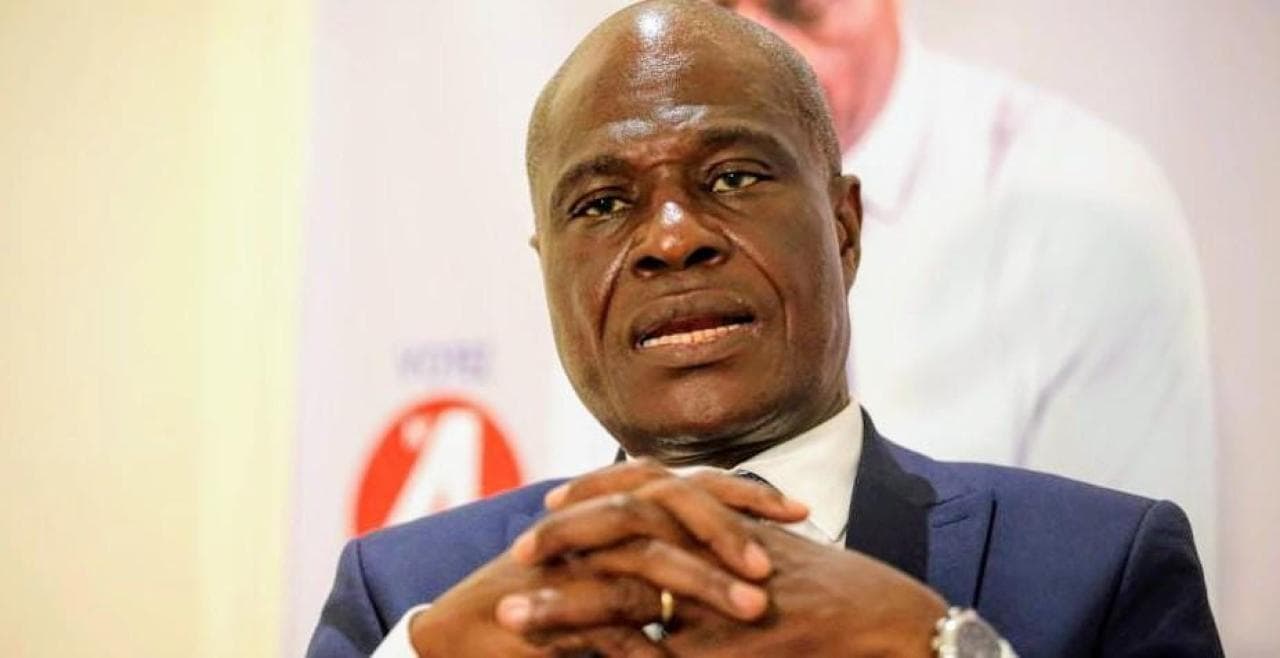 Martin Fayulu, président de l'ECiDé, les mains jointes devant un panneau aux couleurs de son parti lors d'une prise de parole publique