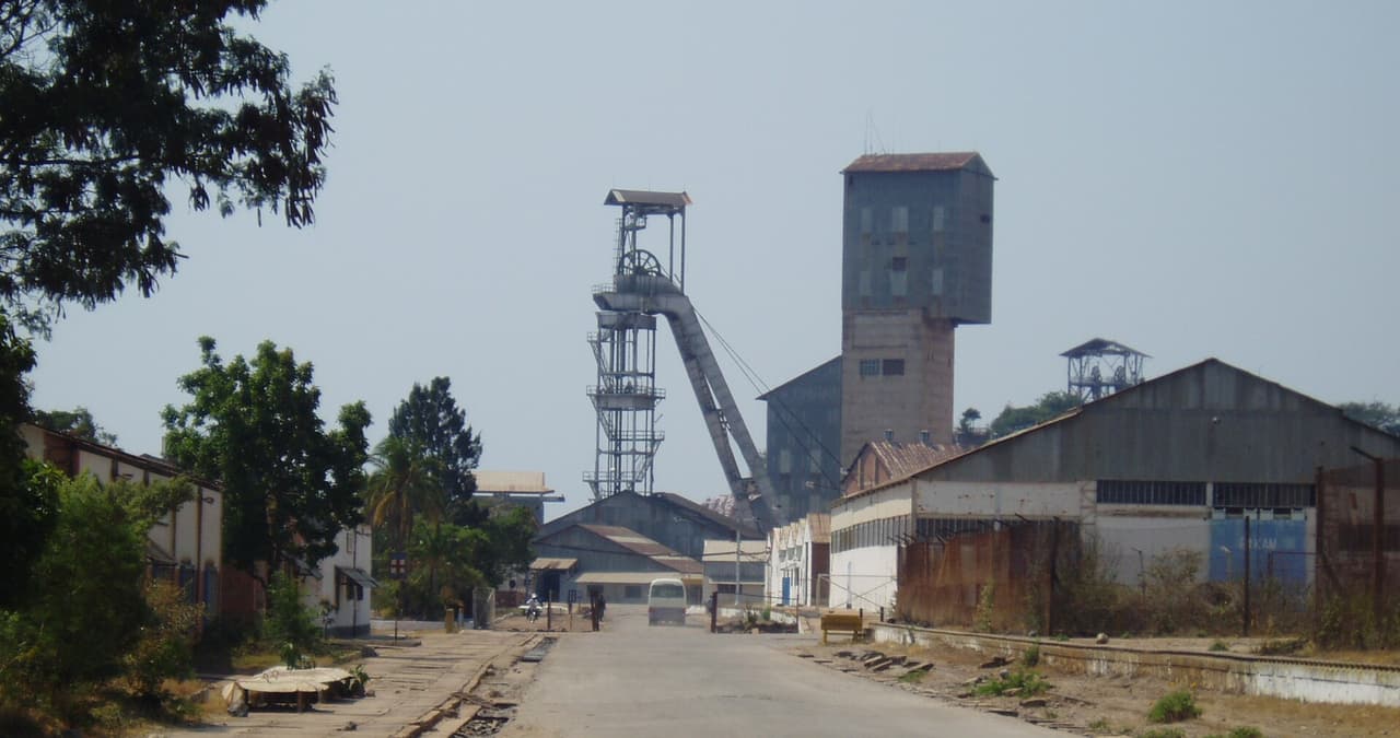Chevalement metallique et batiments industriels de la mine de cuivre de Kamoto, a Kolwezi, le long d une route bordee de voies ferrees.