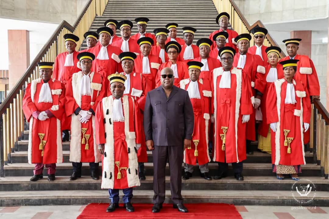 Hauts magistrats congolais en robe rouge d'apparat, coiffés de la toque, réunis sur les marches d'escalier aux côtés du président Félix Tshisekedi en costume sombre lors d'une audience solennelle de la Cour de cassation à Kinshasa.